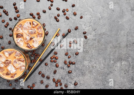 Il freddo di infuso di caffè ghiacciato in bicchiere alto con i chicchi di caffè e le cannucce sul cemento grigio Sfondo. Cioccolato, vaniglia e caramello o cannella caffè ghiacciato in Foto Stock
