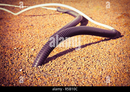 Tubo corrugato con cavo uscente dal suolo Foto Stock