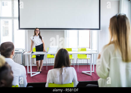 Donna di rispondere durante il team educativo sale riunioni o corsi di formazione aziendale con la donna altoparlante o il pullman Foto Stock