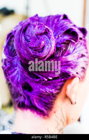 Donna applicando una viola il colore dei capelli shampoo. Foto Stock