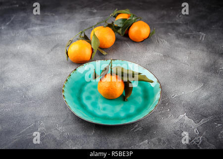 Tangerini - arance, mandarini, clementine, agrumi con foglie di colore verde sulla piastra, spazio di copia Foto Stock