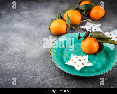 Tangerini - arance, mandarini, clementine, agrumi con foglie di colore verde sulla piastra, spazio di copia Foto Stock