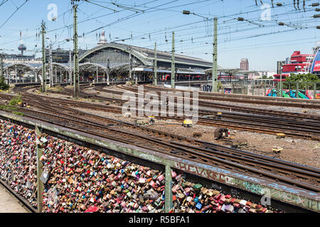 Colonia, Germania. Amore si blocca sulla ringhiera del ponte di Hohenzollern sul Reno. Stazione ferroviaria in background. Foto Stock