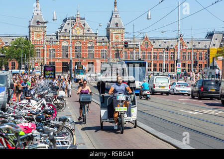 Amsterdam, Paesi Bassi. La stazione ferroviaria e la Strada Damrak scena. Foto Stock