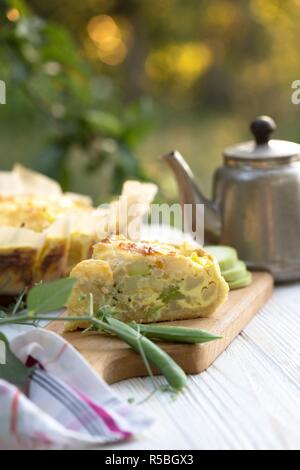 Tart. Torte di verdure - Broccoli, zucchine e formaggio in giardino alla luce del tramonto Foto Stock