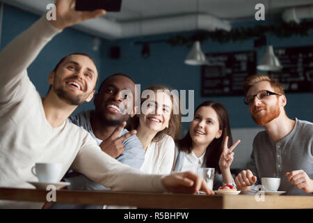 Eccitato amici millenaria rendere selfie sullo smartphone per divertirsi nella caffetteria, Allievi felici sorriso per foto sul telefono riuniti insieme in cafe, div Foto Stock