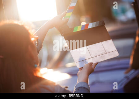 Le riprese in esterni. Donna che mantiene un clapperboard nella parte anteriore della fotocamera, il processo di filmatura. Scena sulla posizione. Foto Stock