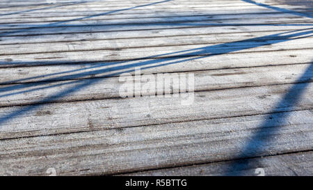 Mattina la brina sul pontile in legno fatto di schede madri. Inverno sfondo di legno Foto Stock