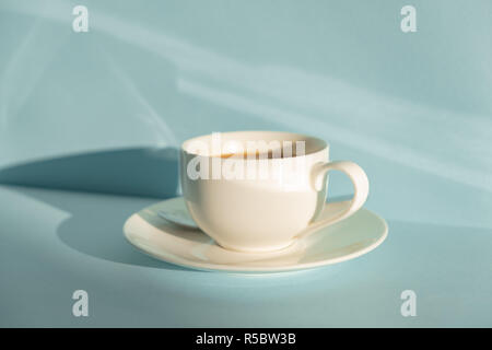 Tazza di caffè fumante seafoam su sfondo verde nella luce naturale del sole. Foto astratte di caldo bere il caffè espresso sul blu pallido-tavolo verde Foto Stock