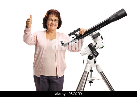 Donna anziana con un telescopio guardando la telecamera e mostrando pollice in alto isolato su sfondo bianco Foto Stock