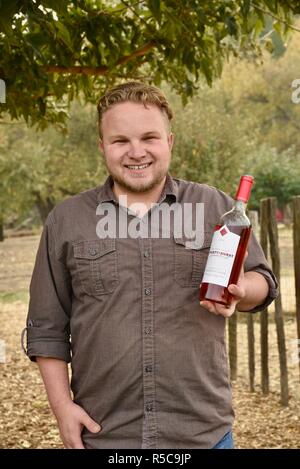 Barbuto sorridente giovane azienda bottiglia di vino, condividendo i campioni al di fuori la sala di degustazione a Truett Hurst Cantina, Sonoma County, Healdsburg, CALIFORNIA, STATI UNITI D'AMERICA Foto Stock