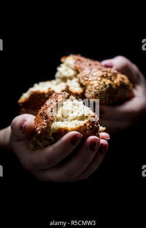 Donna con le mani in mano la condivisione di un filone di pane Foto Stock