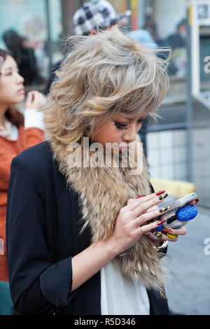 Giappone, Tokyo, Shibuya, giovane donna utilizzando il telefono cellulare Foto Stock