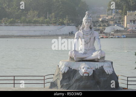 Dio indù Shiva statua a Rishikesh, India. Fiume ganga scorre in background Foto Stock