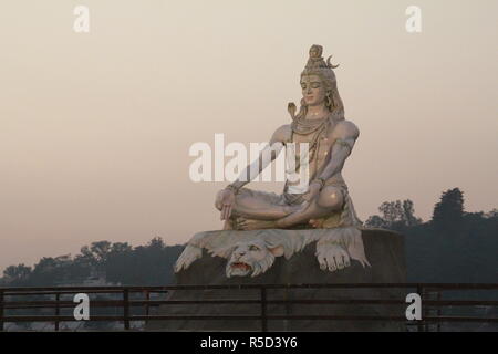 Dio indù Shiva statua a Rishikesh, India. Fiume ganga scorre in background Foto Stock