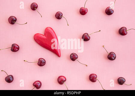 Ciliegie mature e rosso cuore di legno di rosa su sfondo di tela. Foto Stock