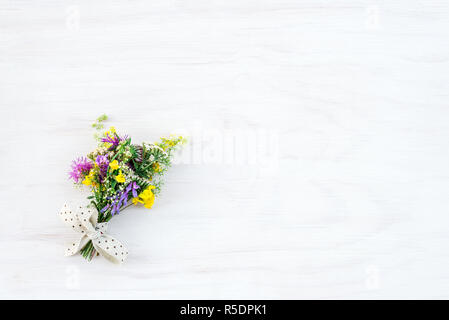 Bouquet di fiori selvatici, il dipinto di bianco sullo sfondo di legno con copia spazio. Foto Stock