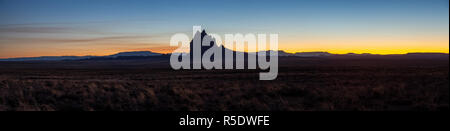 Drammatico paesaggio panoramico vista di un deserto secco con un picco di montagna in background durante una vibrante del tramonto. Prese a Shiprock, New Mexico, unite Foto Stock