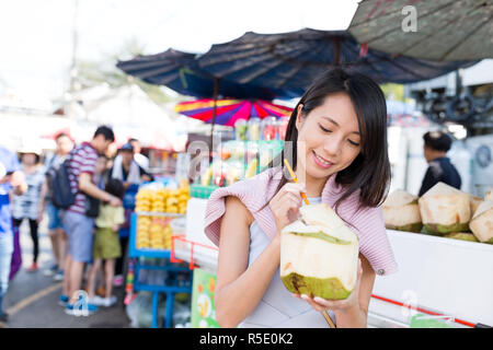 Donna godetevi il cocco succosa in strada del mercato Foto Stock