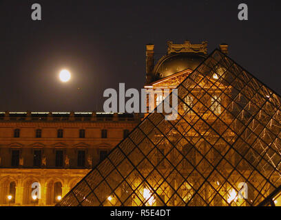 Il Palais du Louvre, Paris, Francia: la piramide nel centro della Cour Napoleone e il Pavillon Denon al di là, con una luna quasi piena che figurano Foto Stock