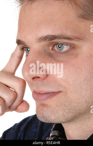 Il ritratto di una giovane mans faccia in un primo piano immagine con un dito sulla sua fronte, bianco occhi blu, isolato per sfondo bianco Foto Stock