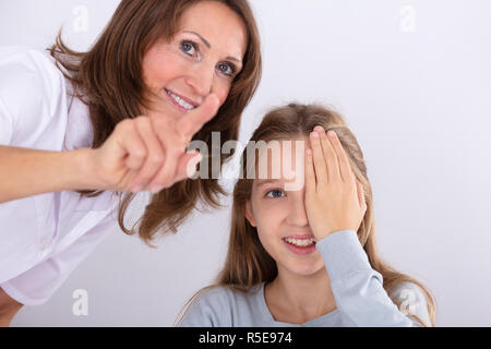 Donna sorridente all'ottico optometrista assistere ragazza mentre si verifica la vista in clinica Foto Stock