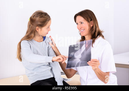 Close-up di ragazza Guardando femmina matura medico tenendo osso X-ray Foto Stock