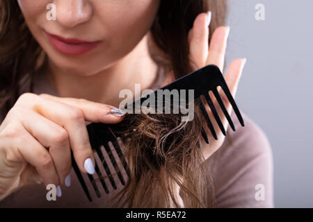 Close-up di una donna di pettinatura a mano i capelli con il pettine Foto Stock