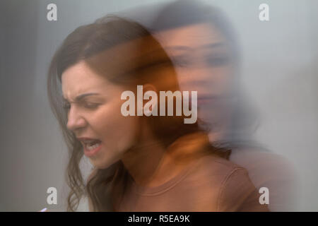 Esposizione multipla di un arrabbiato donna su sfondo grigio Foto Stock