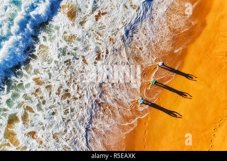 Gruppo di attivi sport sano persone che esercitano presso le onde che si infrangono sulle rive dell'oceano Pacifico largo sabbie di spiagge settentrionali in Australia, a Sydney, Foto Stock