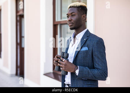 Determinato africana imprenditore americano utilizzando il binocolo in office Foto Stock