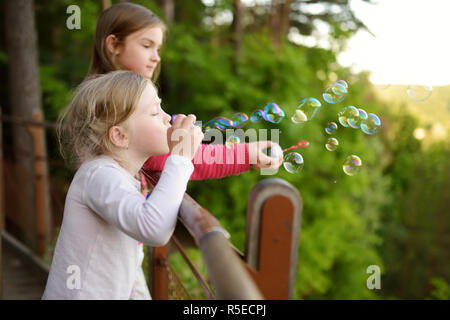Carino bambine soffiando bolle di sapone su un tramonto all'aperto nella bella giornata d'estate. Divertenti attività per i bambini. Foto Stock