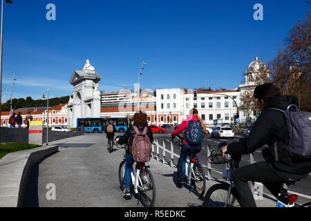 I ciclisti utilizzano la pista ciclabile accanto al Paseo del Virgen del Puerto in prossimità dell'arco di Puerta de San Vincente e della stazione Principe Pio, Madrid, Spagna Foto Stock