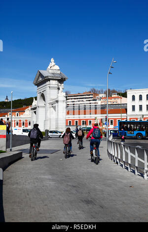 I ciclisti utilizzano la pista ciclabile accanto al Paseo del Virgen del Puerto in prossimità dell'arco di Puerta de San Vincente e della stazione Principe Pio, Madrid, Spagna Foto Stock