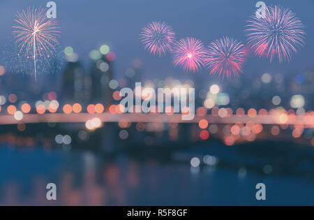 Fuochi d'artificio colorati su sfocato bokeh luci della città sullo sfondo Foto Stock