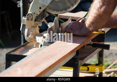 L'uomo la misurazione di un asse di legno al di fuori nel sole Foto Stock