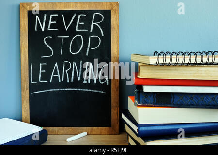 Lavagna con segno non smettere mai di imparare e libri. Foto Stock