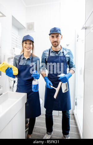 Ritratto di una giovane coppia come pulitori professionali in uniforme blu bagno di pulizia. Il servizio di pulizia concept Foto Stock