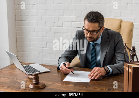 Angolo di alta vista del concentrato avvocato maschio in occhiali lavora con documento di Office Foto Stock