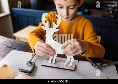 Il ragazzo sta facendo un cervo in legno figurine Foto Stock