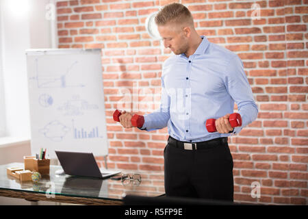 Imprenditore esercita con manubri Foto Stock