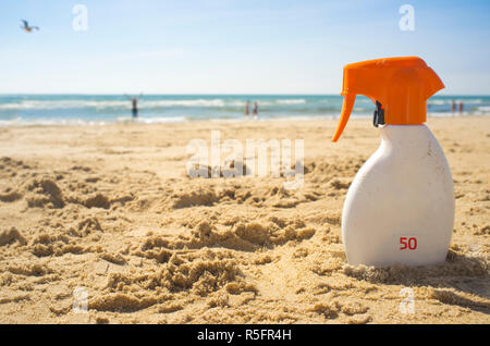 Crema di protezione solare con fattore di protezione solare o SPF 50 sulla spiaggia di sabbia. Persone su sfondo Foto Stock