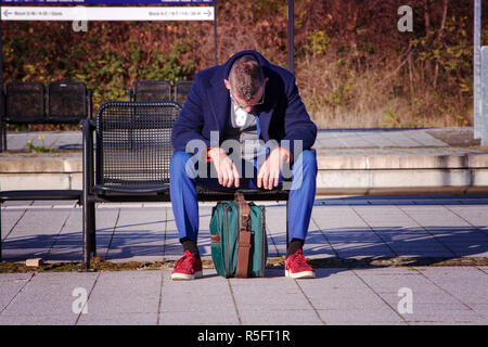 Imprenditore in tuta blu in attesa alla stazione ferroviaria cercando esaurito Foto Stock