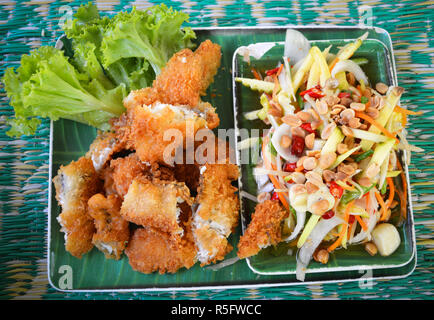 Pesce fritto croccante insalata piccante salsa / pesce fritto di filetto con briciole di pane e verdure a green mango insalata piccante peperoncino rosso e arachide sulla parte superiore - slic Foto Stock