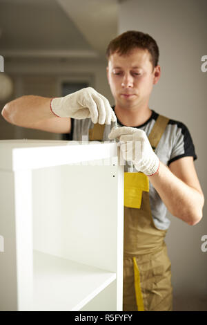 L'uomo bianco di montaggio armadio in background in camera Foto Stock