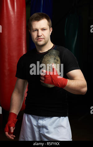 Ritratto del boxer caucasici con guanti su boxe sacchi di sabbia sullo sfondo Foto Stock