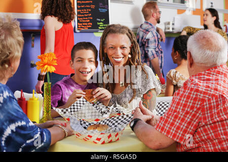 La madre e il suo figlio adolescente a pranzo con gli anziani Foto Stock