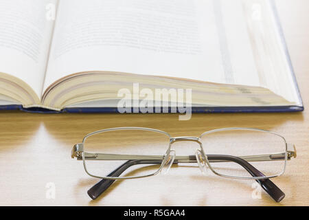 Chiudere i bicchieri e un libro sulla scrivania Foto Stock