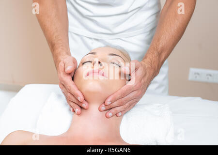 Terapista del sesso maschile facendo il massaggio del viso di donna in un salone di bellezza Foto Stock