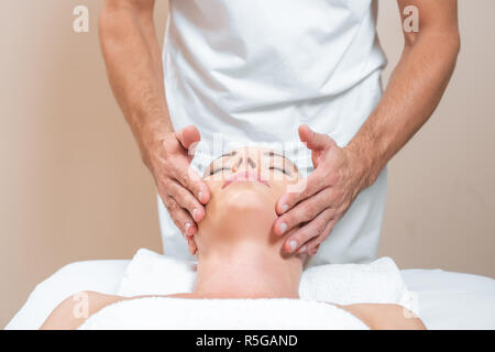 Terapista del sesso maschile facendo il massaggio del viso di donna Foto Stock